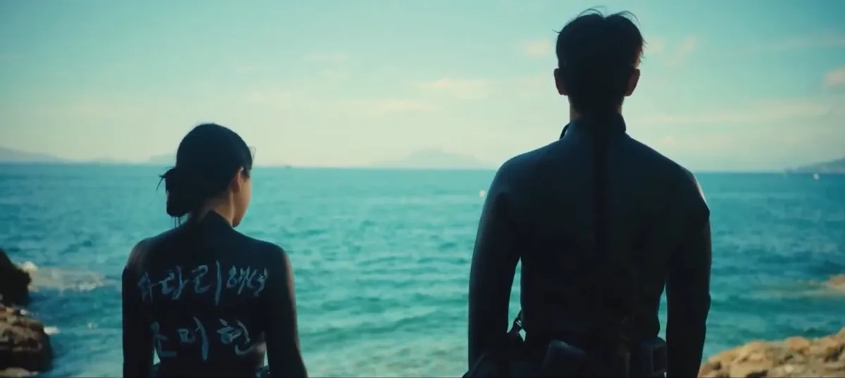 An Na and Deok standing next to each other on a rocky shoreline